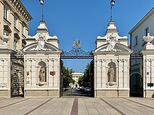 Portail d'entrée composé de deux colonnes carrées et d'un grillage.