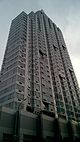 DKLB BKLN, a high-rise clad in stone and blue glass with curved corners, viewed from street level