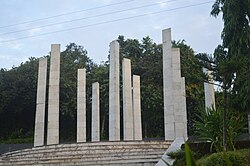 Sculpture with columns of stone with trees behind