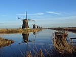 Five windmills along the left bank of a canal