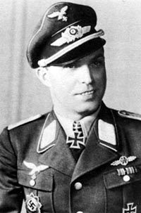 The black and white photo of a man, shown from the front. He wears a military uniform with an Iron Cross displayed at the front of his shirt collar.