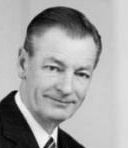 Black and white photo of clean-shaven man with short hair, in business suit