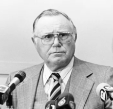 A black and white portrait of Robert J. Parins in a suit and tie