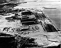 Naval Air Station, Kaneohe Bay, after the Pearl Harbor raid. With burnt hanger, seaplane PBY, the 5 seaplane ramps are visible.