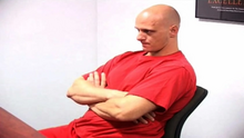 Johnson in red prison uniform sitting on a chair at a table