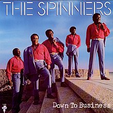 The group standing on stairs in matching red and blue suits