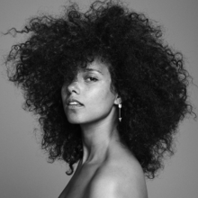 The black and white picture shows a woman with black curly hair, wearing a silver earring and looking straight at the camera.