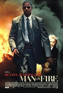 A man in a suit and sunglasses walking away from a fiery blaze, his arm held out to guard a small blonde girl