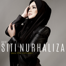 Siti Nurhaliza menatap di arah kanan sambil meletakkan tangan di siku dan pipinya.