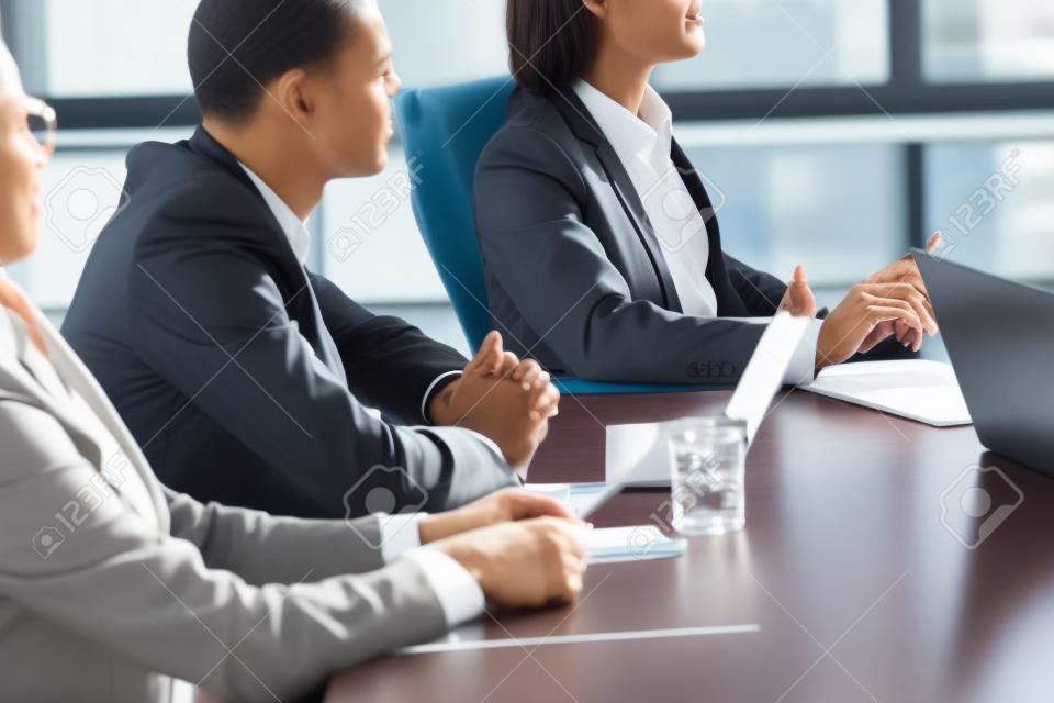 Attentive diverse businesspeople sitting at conference table focused on listening at meeting, multiracial corporate team training, partners group at negotiations or business seminar concept, close up