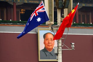 The Australian national flag flies next to the Chinese national flag in front of the giant portrait of former Chairman Mao Zedon