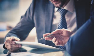 Image of two young businessmen using touchpad at meeting