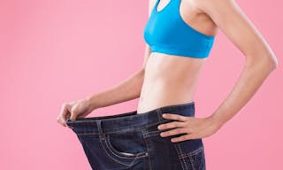 woman wear jeans and show weight loss on the pink background