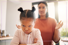 Angry little girl, unhappy and upset after fight or being scolded by mother, frowning with attitude and arms crossed