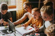 Woman sat with three kids drawing