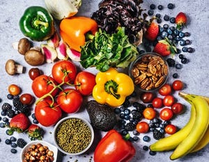 fresh vegetables, fruits, beans, and nuts on gray background