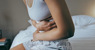 menstruation, stomach ache and hands of woman in bedroom for indigestion, cramps and illness frustrated, gas and stress with girl on bed for constipation, bloating and intestine problems at home