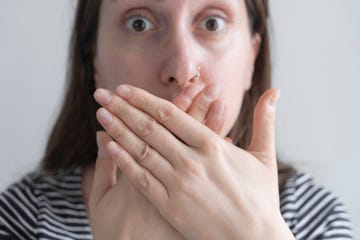 woman is hiding her mouth with her hands