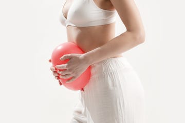 young woman holding balloon as a sign of an stomach inflation, bloating and menstrual cramps concept