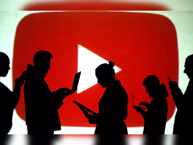 FILE PHOTO: Silhouettes of laptop and mobile device users next to a screen projection of the YouTube logo in this picture illustration