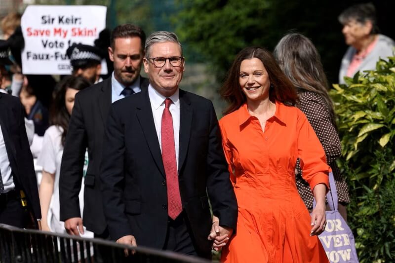英國在野黨工黨領袖凱爾（前左）和妻子（前右）4日走出投票站。（路透社）