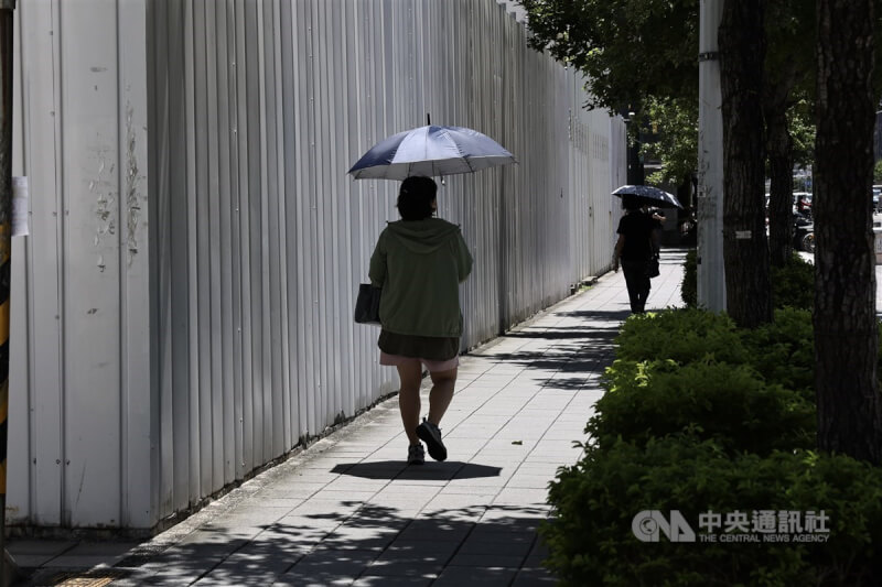 圖為���市松山區民眾穿外套、撐傘防曬。中央社記者翁睿坤攝 113年7月12日