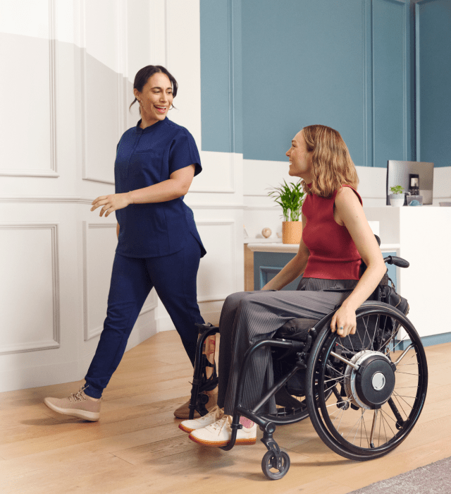 A One Medical clinician talks with a patient in a wheelchair inside of a One Medical office