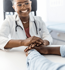 Physician smiles and holds a patient's hands