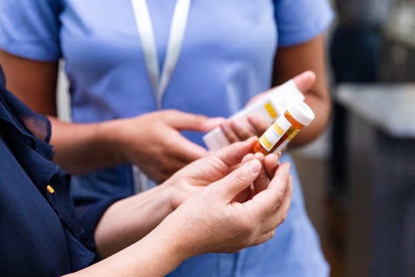 Female pharmacist discusses dosage instructions and drug side effects with a patient.