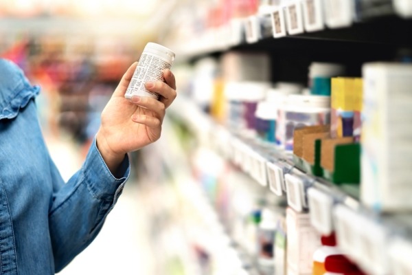 Customer in pharmacy holding medicine bottle. 