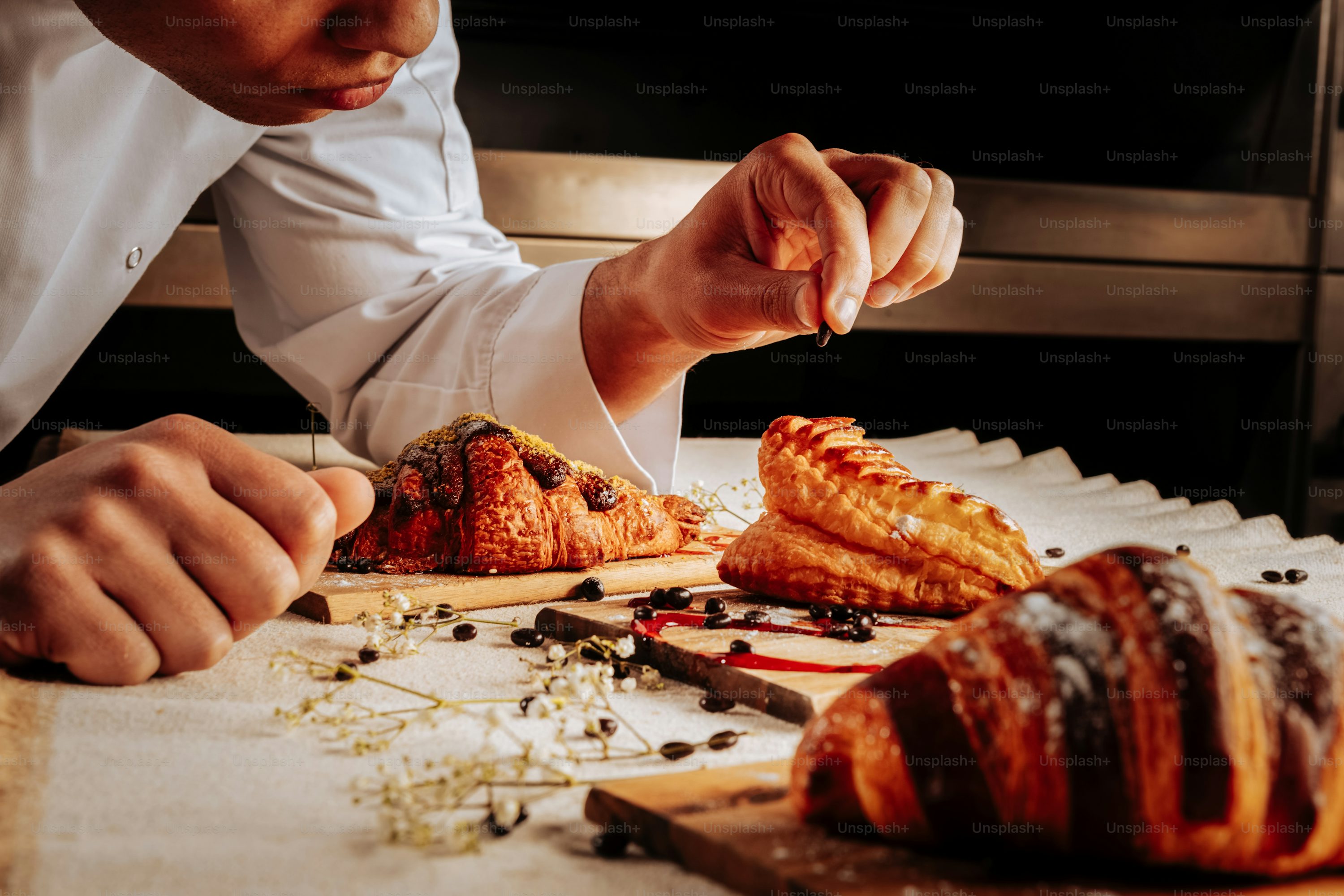 Croissants and puff. Baker decorating croissants and cream puff on wooden plates