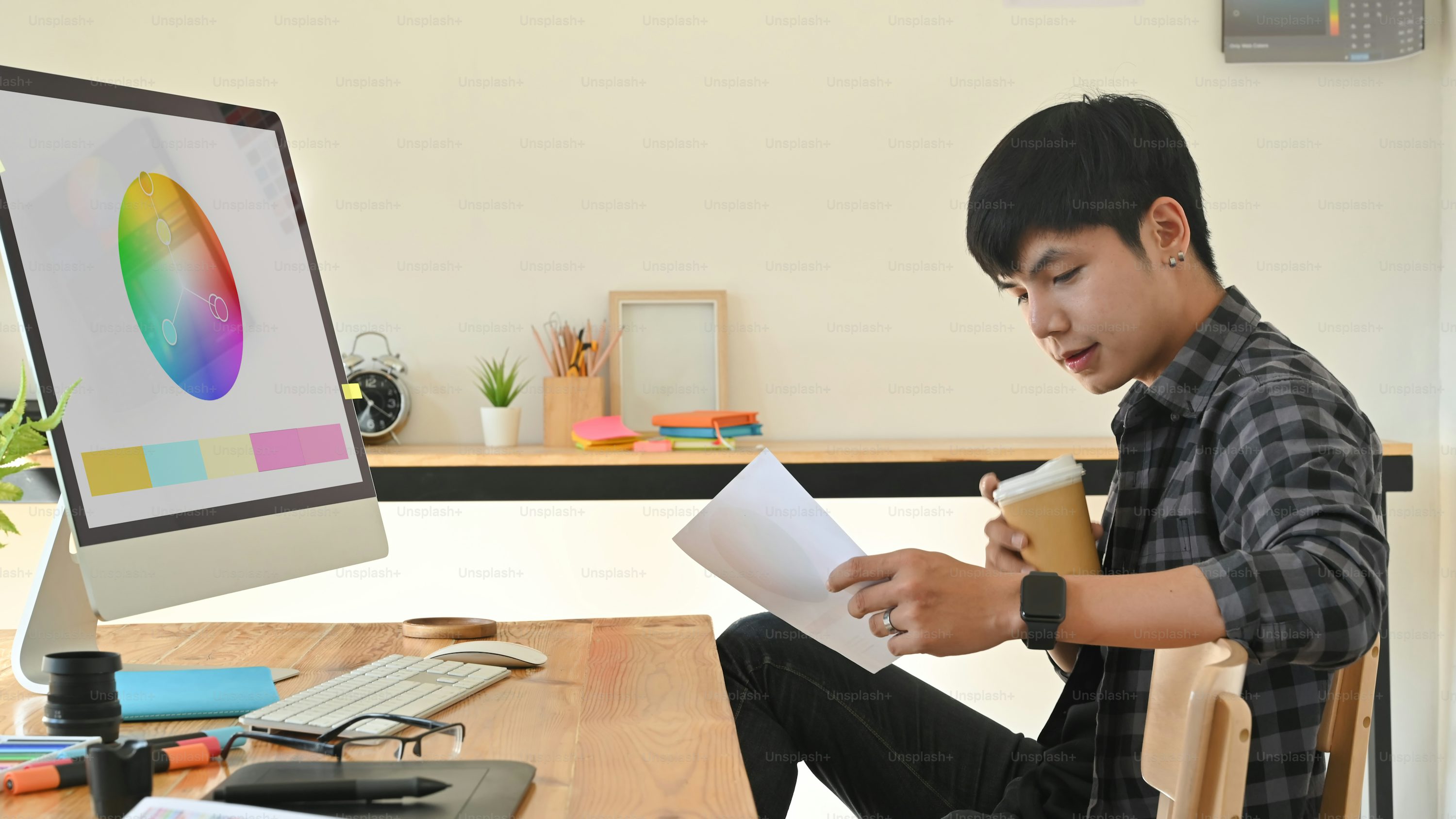 Creative man working with paper colour and holding coffee cup on creativity workplace.