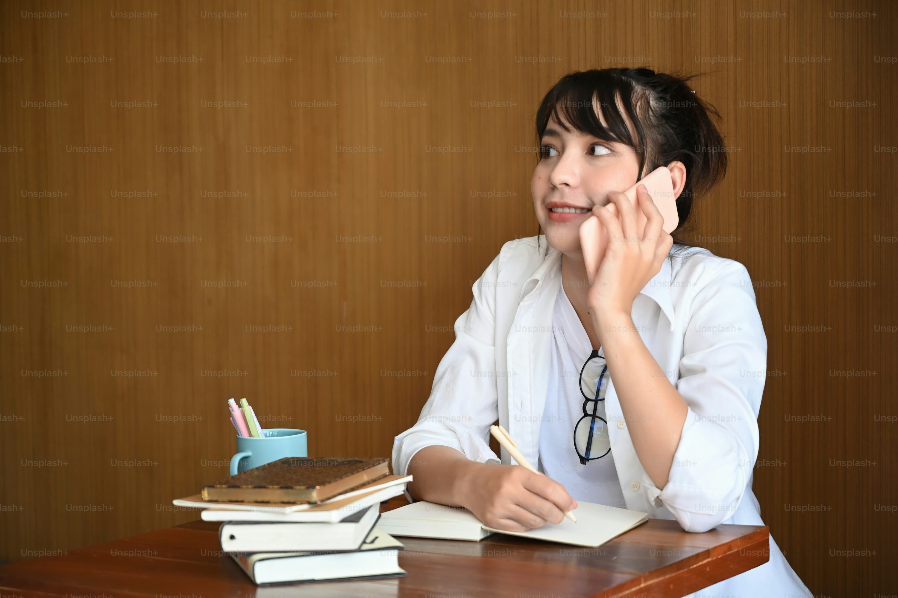 Young asian woman talking on mobile phone while sitting at cafe.