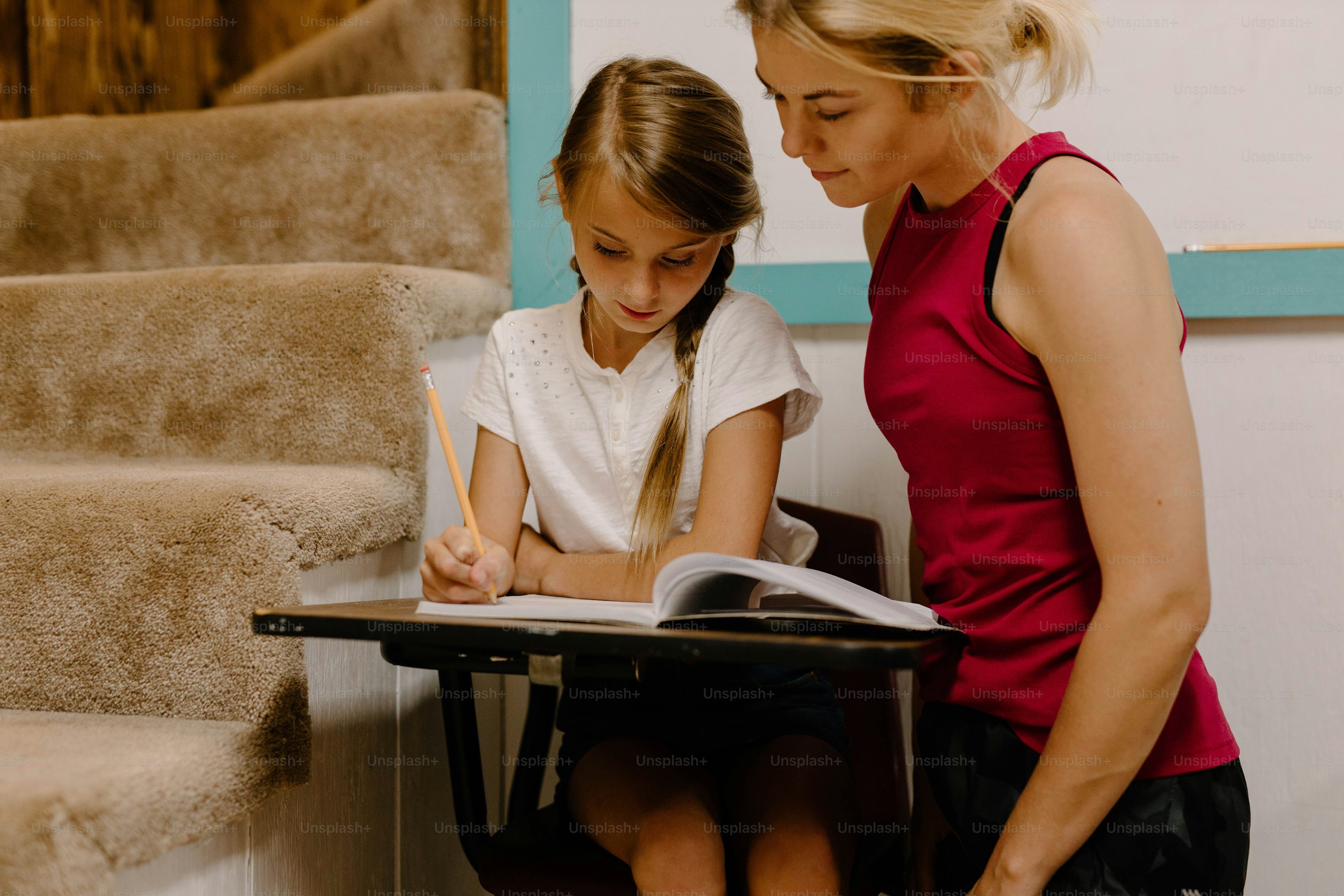 a woman and a little girl sitting at a table with a book