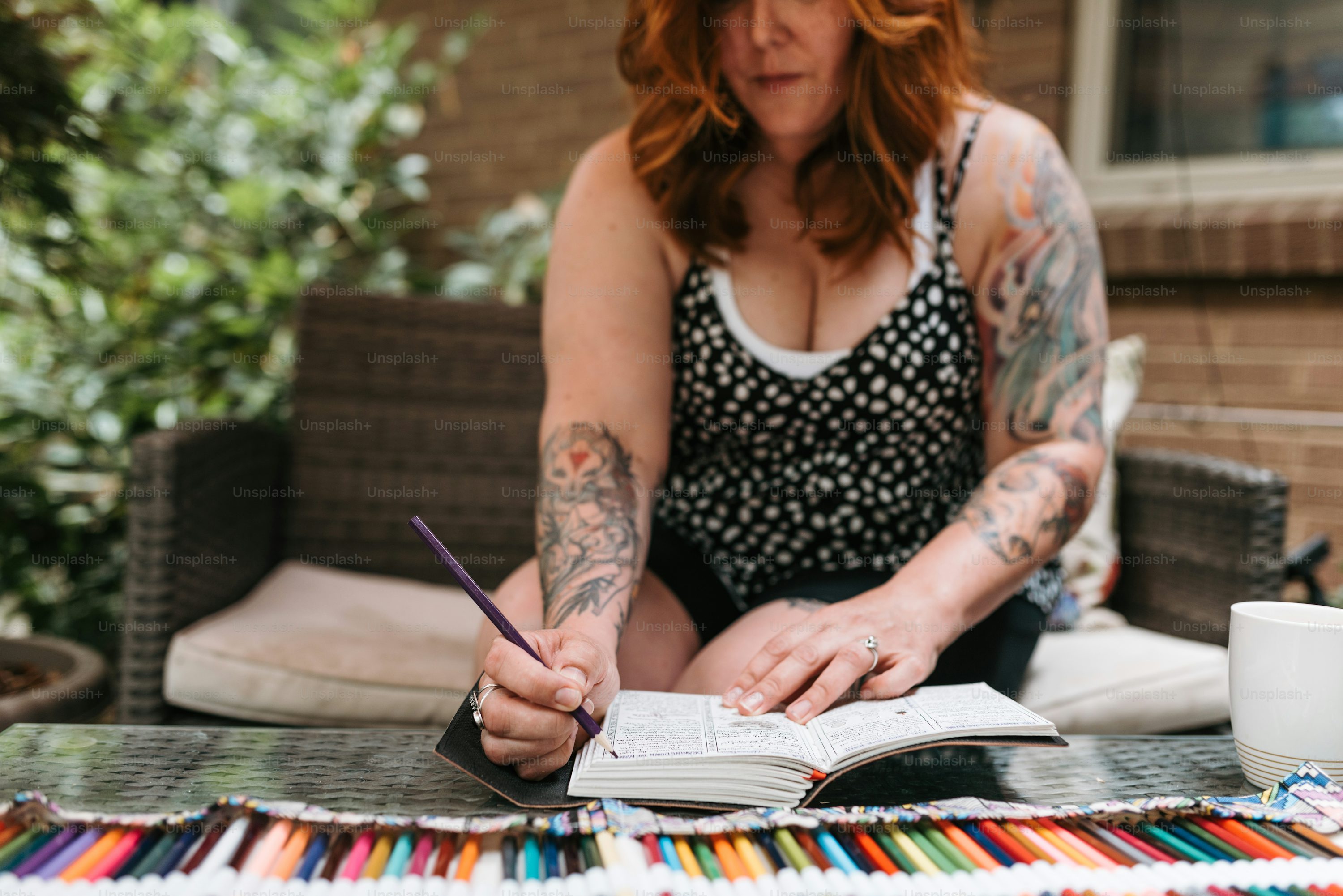 a woman sitting at a table with a book and pen