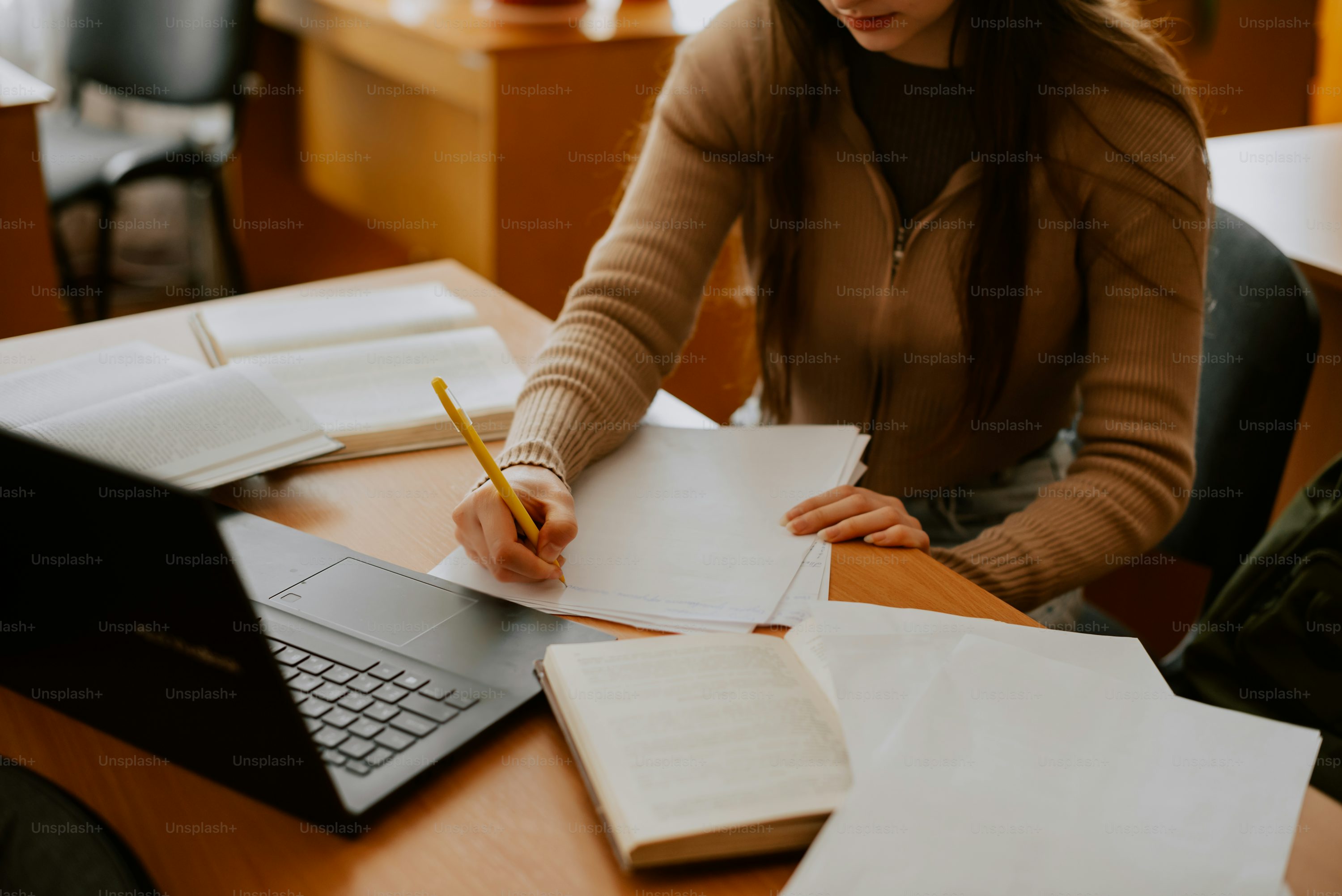 a woman sitting at a desk writing on a notebook