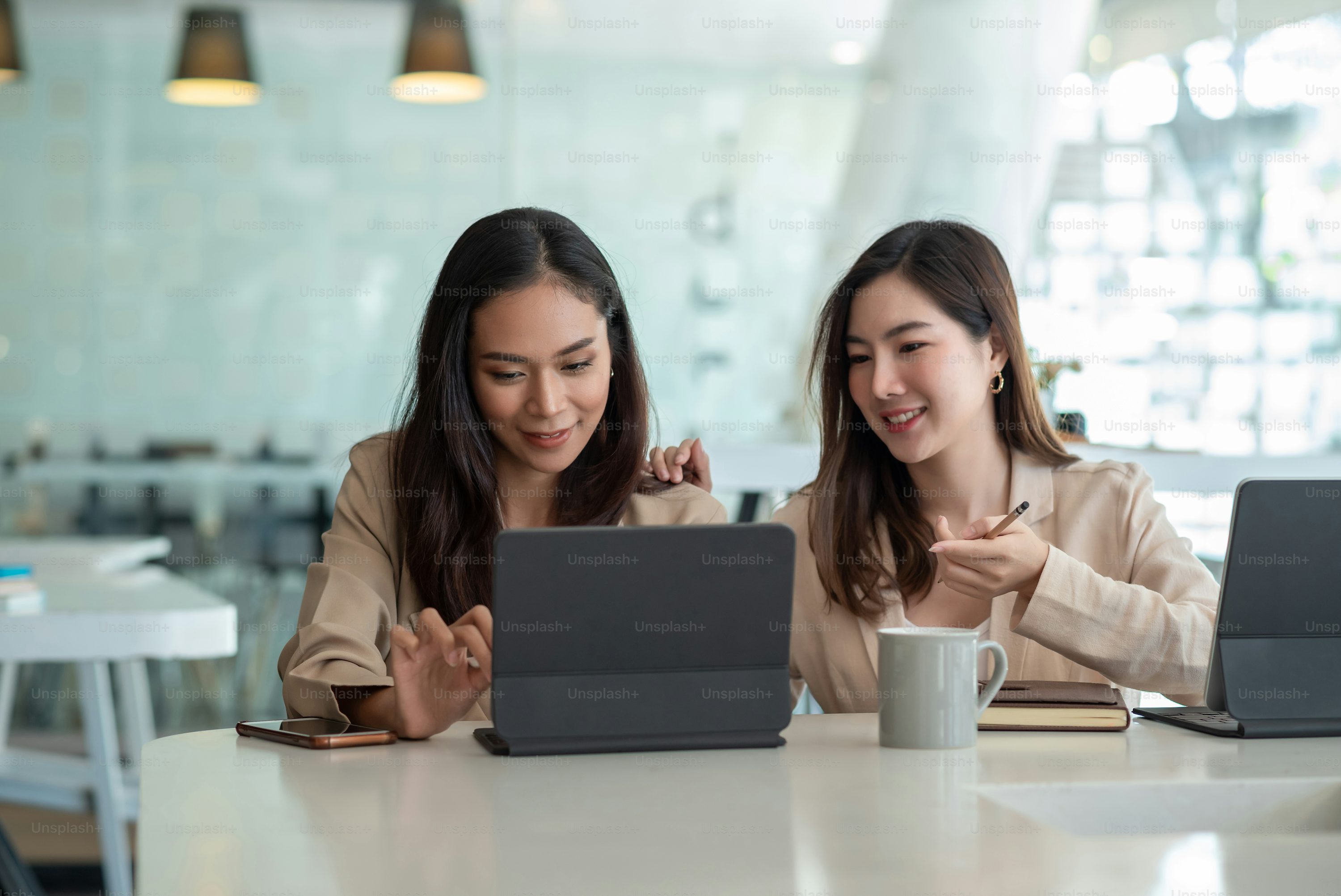 Two young Asian businesswoman is happy working on presentations using papers and tablet placed at the office.