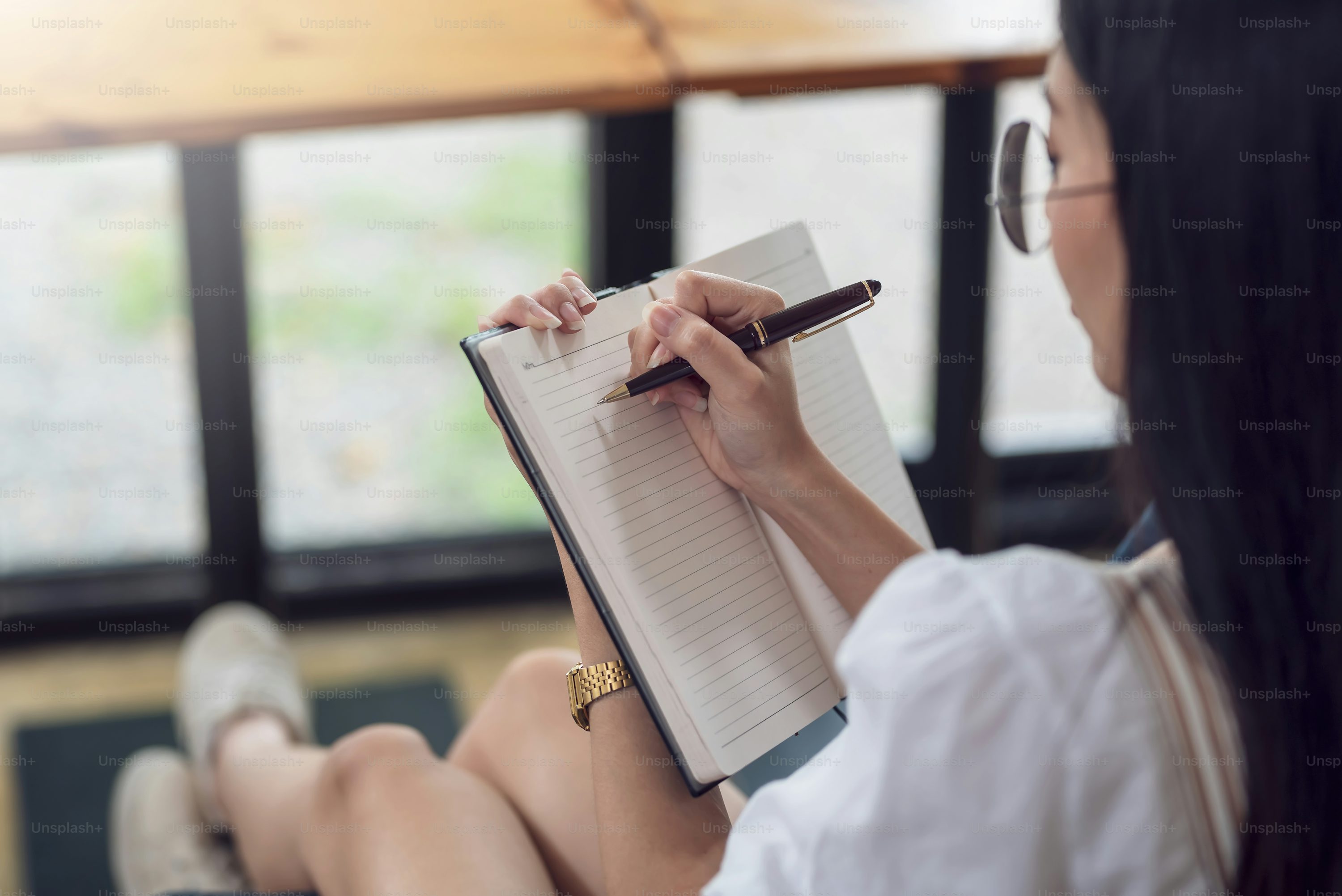 Close-up of a woman hand holding a pen with a notebook  taking note concept.