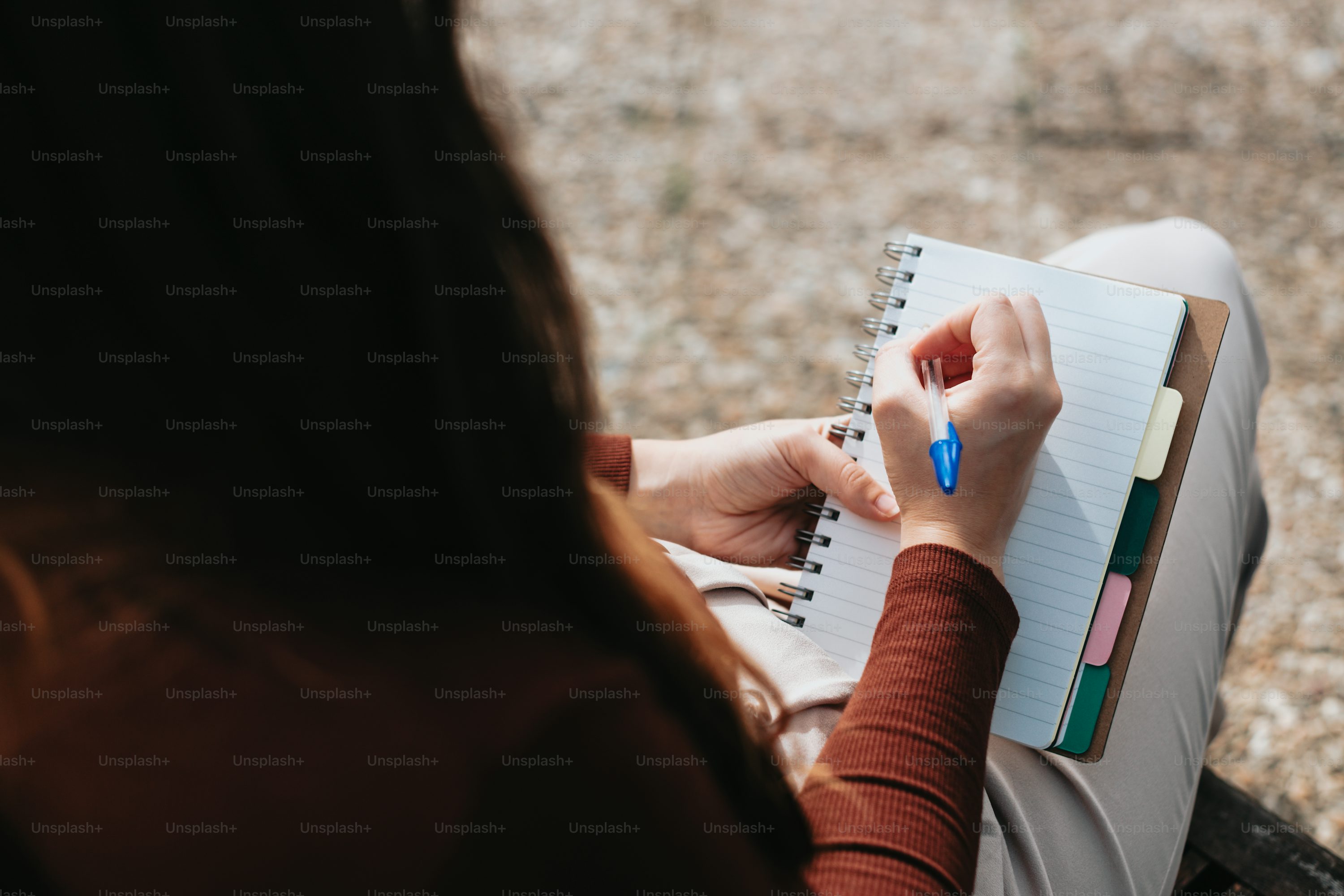 a woman sitting on a bench writing on a notebook