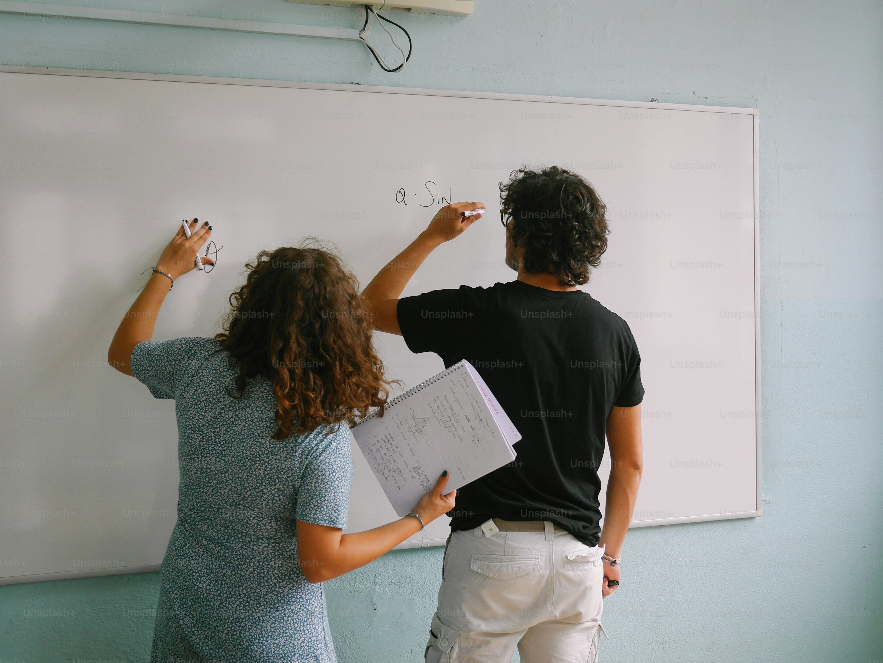 a man and a woman writing on a whiteboard