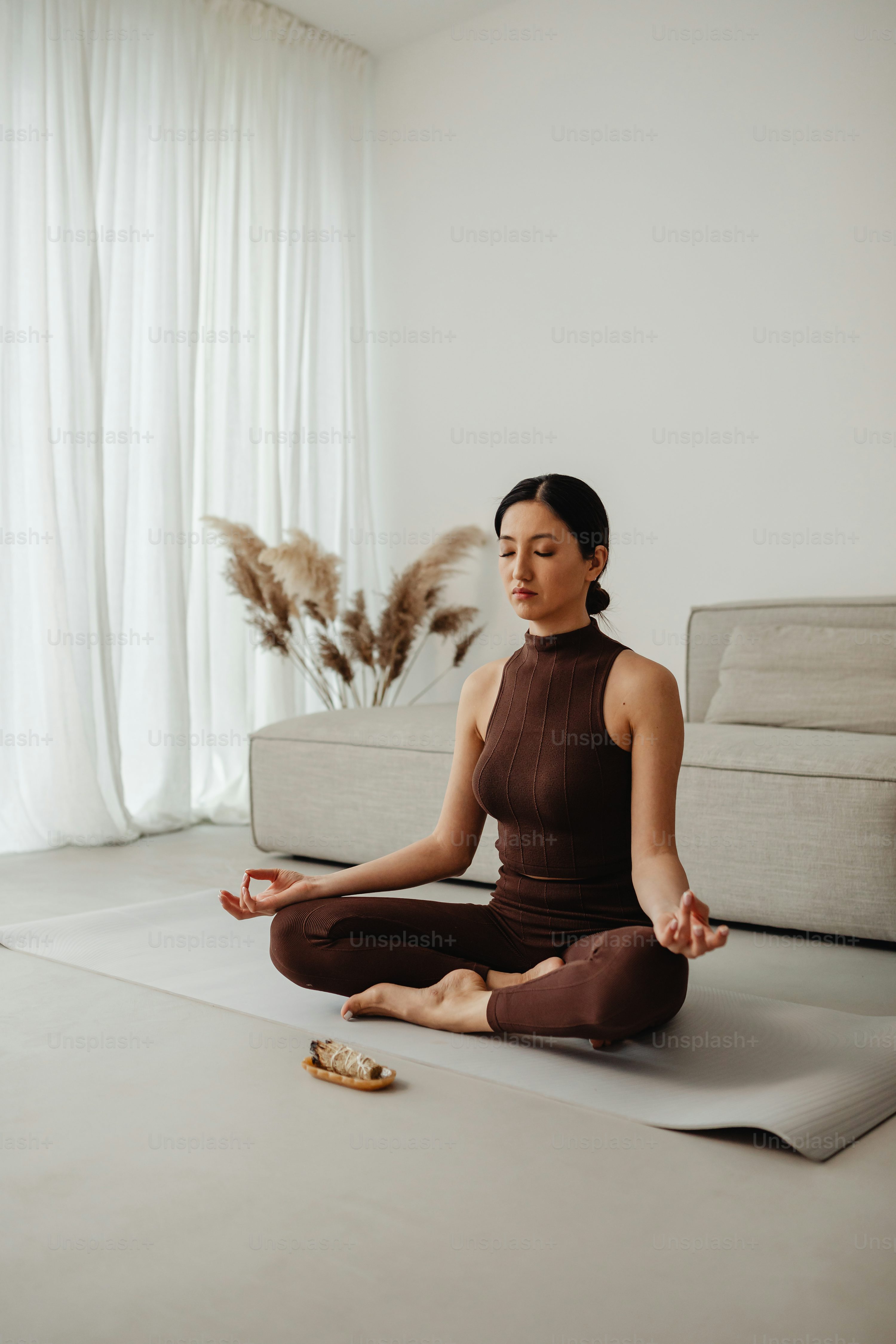 a woman sitting on a yoga mat in a living room