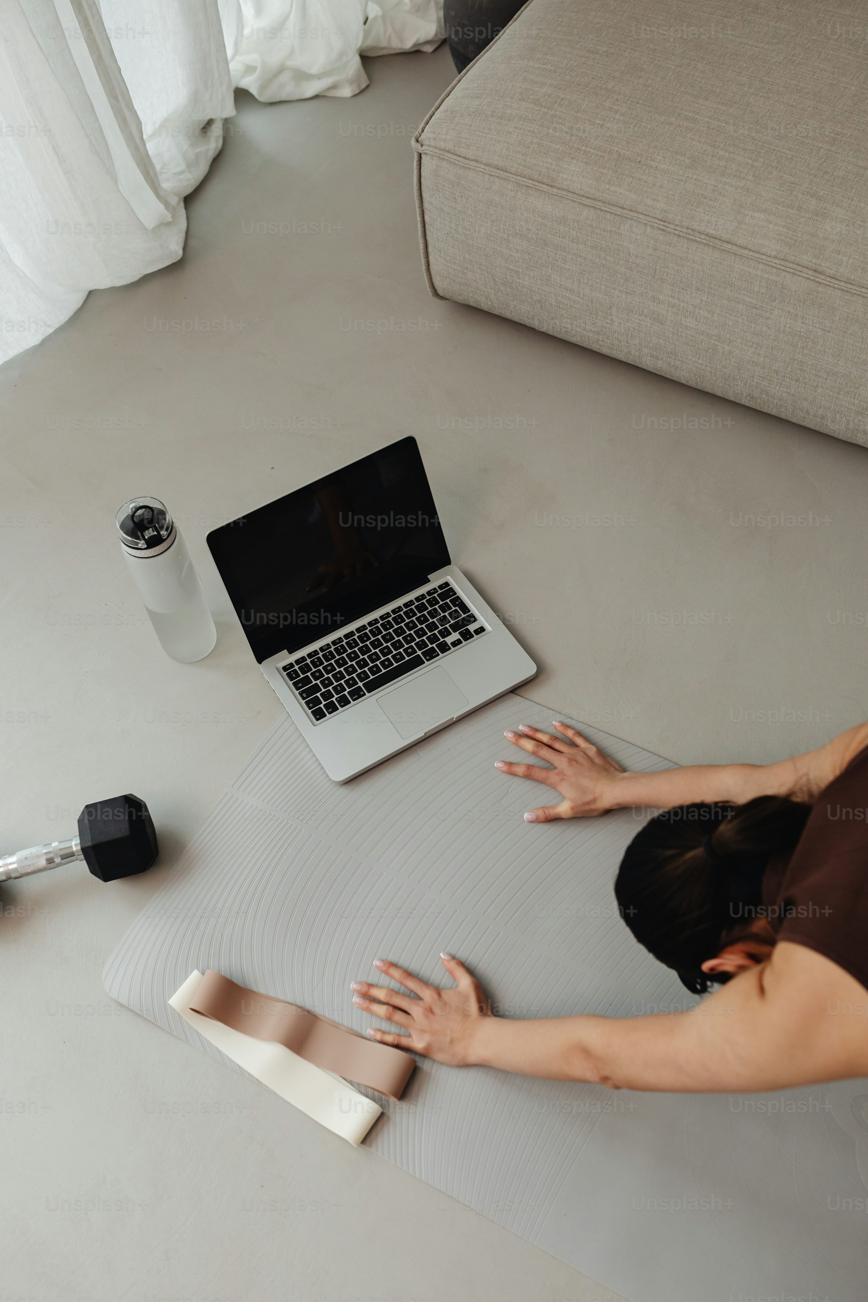 a woman laying on a yoga mat using a laptop