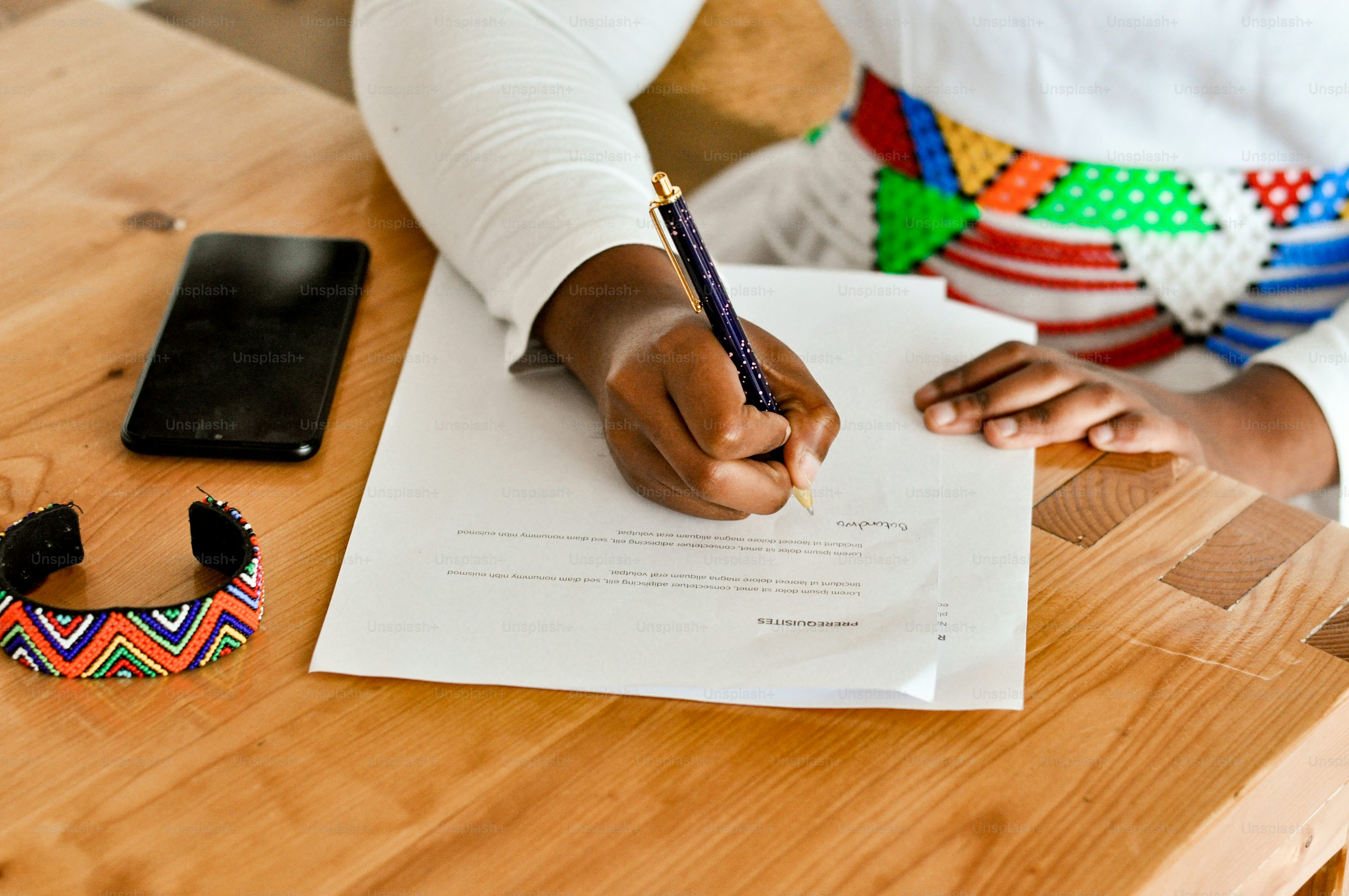 a person sitting at a table writing on a piece of paper