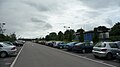 English: Park of the car park at the London Road park and ride site, in Salisbury, Wiltshire, which is served by route 504. The site is unusual in that the waiting room is sited by the main road - passengers park in the car park and walk up to the waiting room. Buses do not enter the site, instead turning on a roundabout and using a simple layby to stop in. The only downside is that while you wait for the bus, a constant stream of noisy traffic goes past.