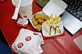 A typical meal with a hamburger, french fries, fried chicken, barbecue sauce, and a beverage. (Japan)