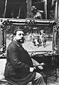 El pintor José Llaneces en su taller en 1909, posa ante un típico tableautin preciosista o de casacón, ya enmarcado y dispuesto para su colocación en cualquier "gabinete" de una casa particular.