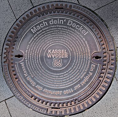 Manhole cover with inscription for the 1100th anniversary of the city of Kassel "Make your cover", Germany