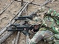 Two Force Recon Marines lying prone. Both are outfitted for Greenside operations, and both are utilizing the CamelBak MULE Hydration Carrier/Backpack. Both Marines are using similar weapons: M4A1s outfitted with M203 grenade launchers. Man in foreground also seems to have a SureFire M500B Millennium light mounted on his weapon, with the bottom handguard removed to accommodate the M203.