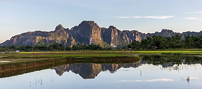 Water reflection of karst mountains at golden hour in Vang Vieng Laos (panoramic).jpg