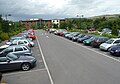 English: Park of the car park at the London Road park and ride site, in Salisbury, Wiltshire, which is served by route 504. The site is unusual in that the waiting room is sited by the main road - passengers park in the car park and walk up to the waiting room. Buses do not enter the site, instead turning on a roundabout and using a simple layby to stop in. The only downside is that while you wait for the bus, a constant stream of noisy traffic goes past.